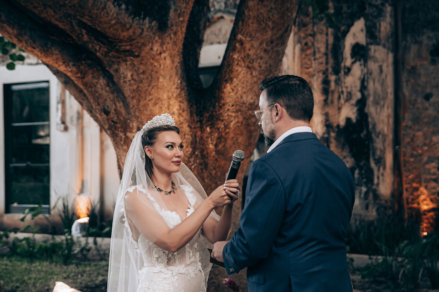 Romantic wedding couple shares intimate moments in a garden setting illuminated by warm evening light.