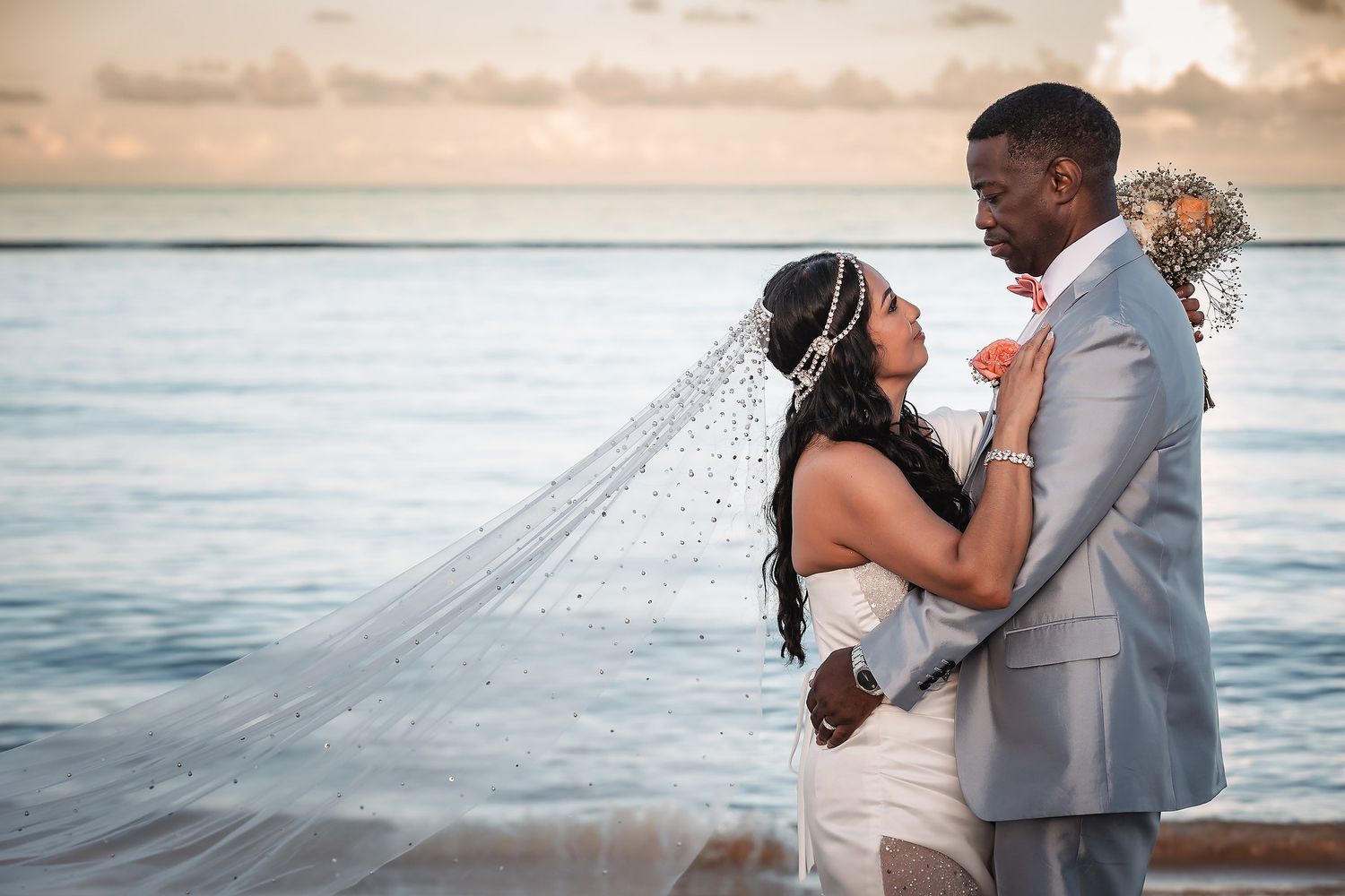 Intimate beach wedding moment with couple against ocean backdrop at sunset.