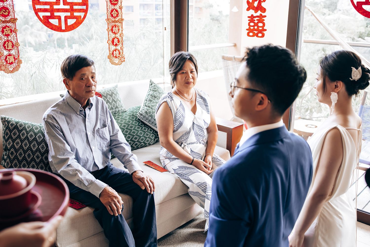 Traditional Chinese wedding tea ceremony with decorative red double happiness symbols in the background.