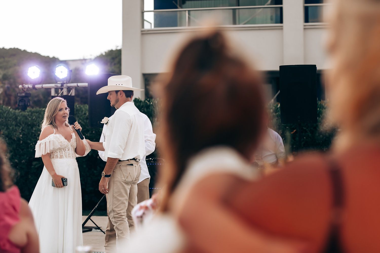 Wedding guests dance together at an outdoor reception celebration with string lights overhead.
