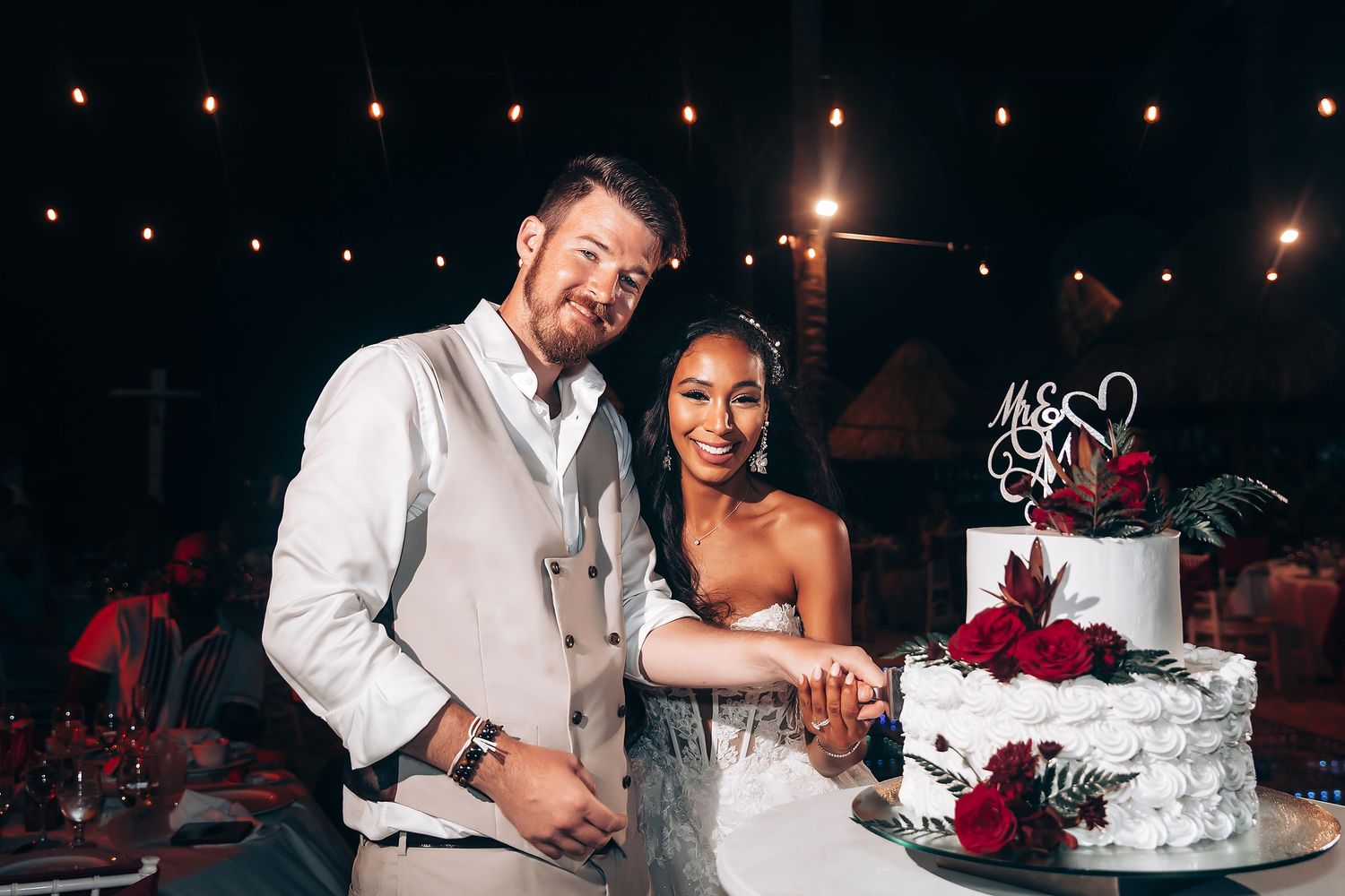 Couple cutting their wedding cake at a nighttime reception.