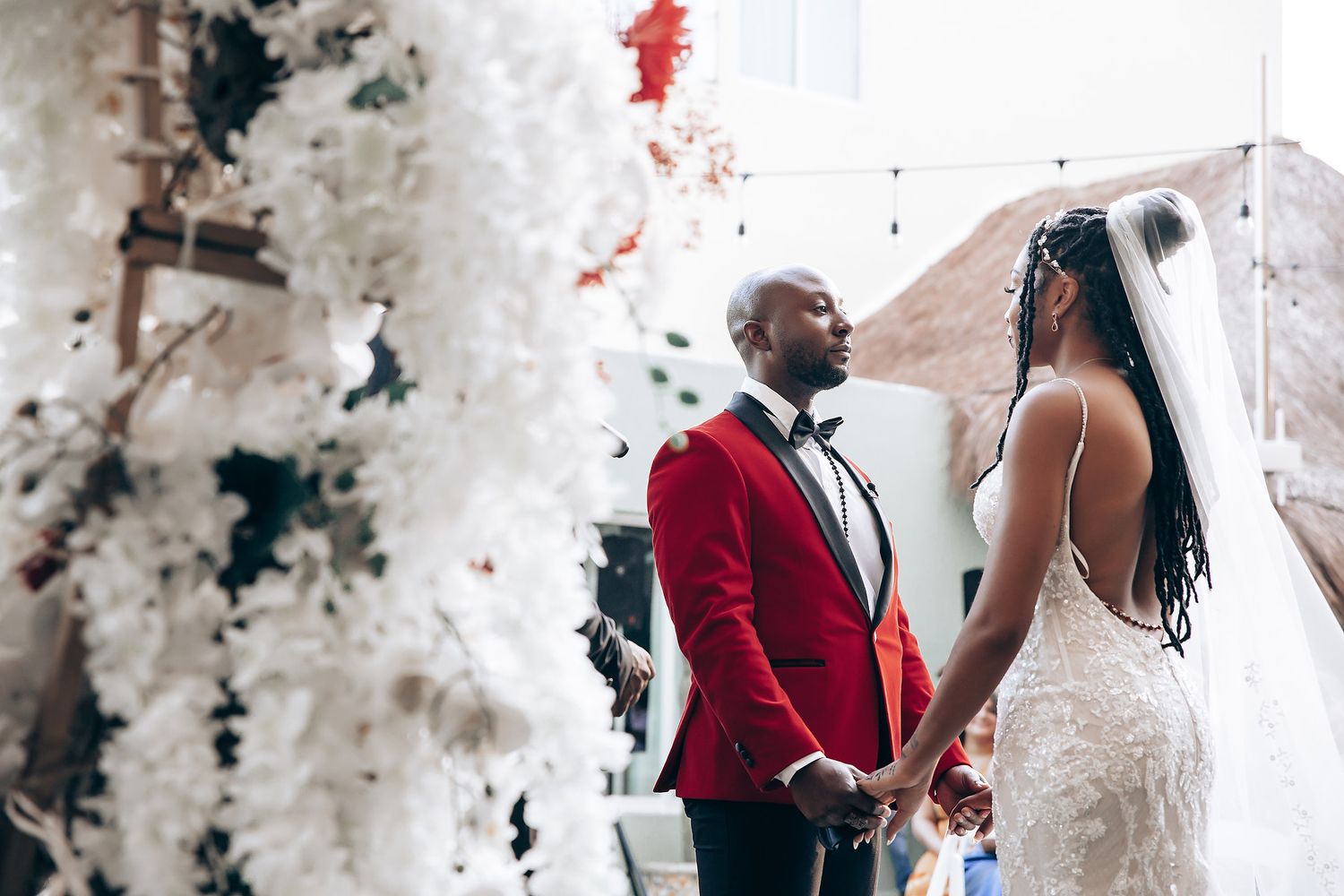 A couple shares a romantic dance moment during their wedding celebration in elegant red and white attire.