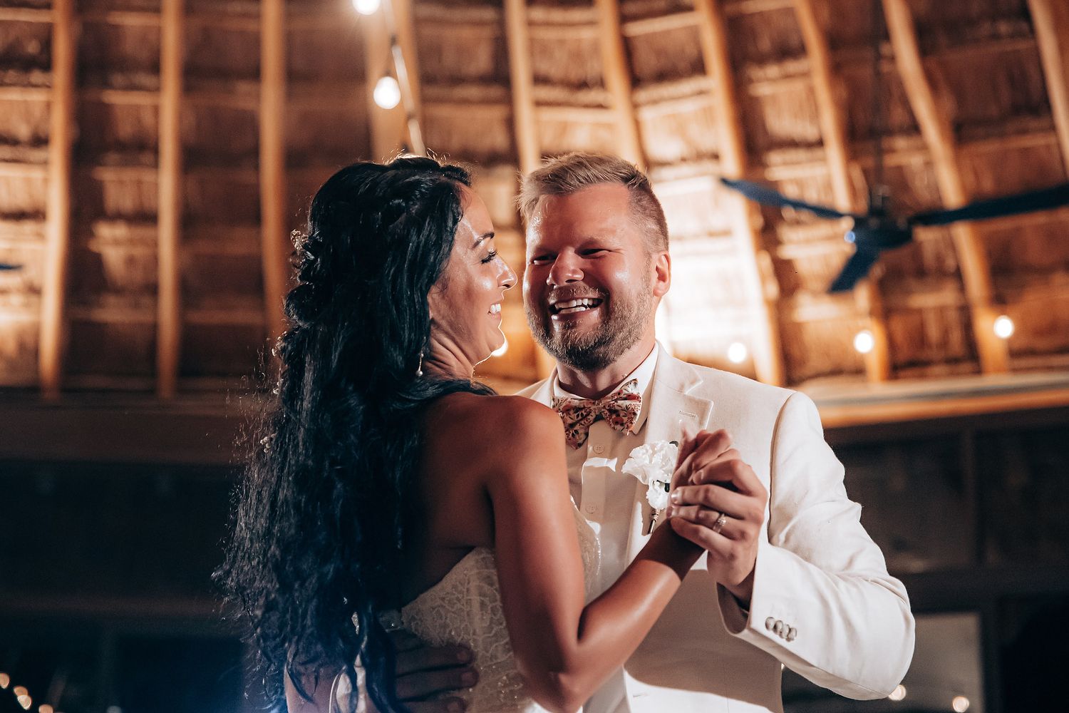 Romantic evening scene under a thatched roof palapa with warm lighting and intimate atmosphere.