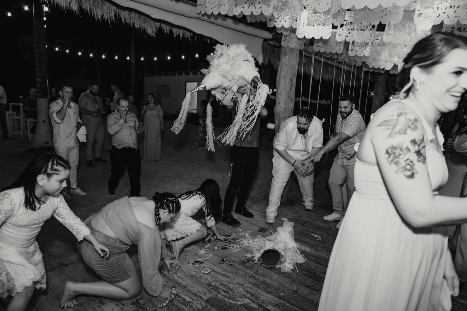 Lively black and white wedding reception dance floor scene with guests enjoying a piñata.