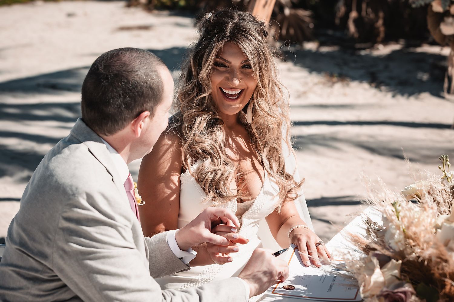 Wedding couple shares intimate moments on a sandy beach with palm trees in the background.