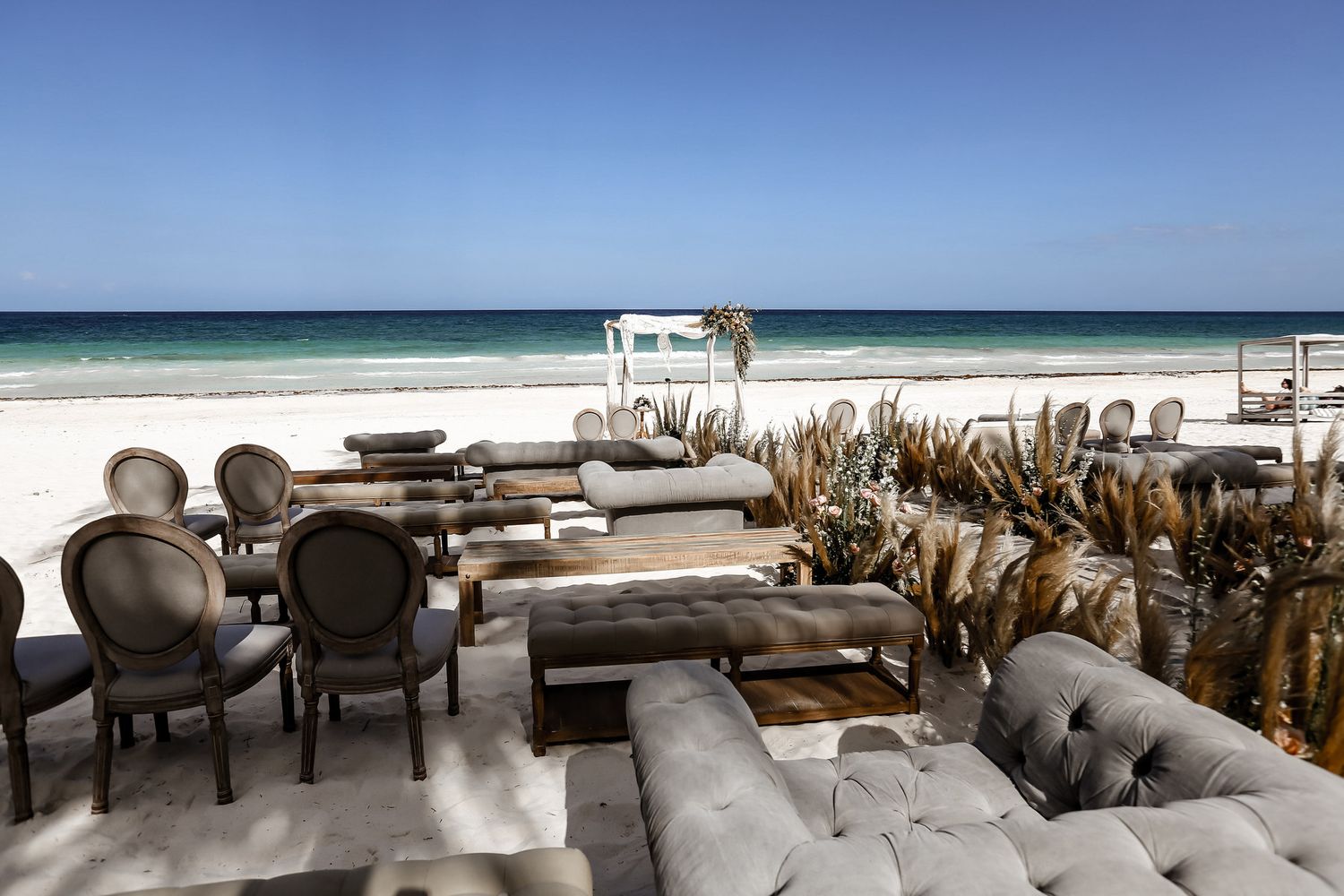 Beachfront wedding reception setup with elegant chairs and ocean view.