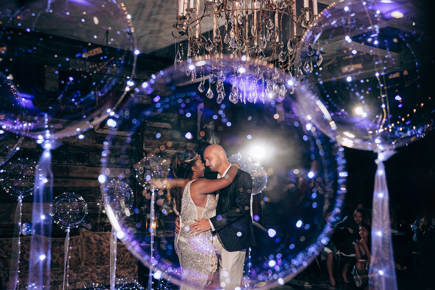 A couple shares their first dance under a magical display of blue lights and sparkles in an elegant ballroom setting.