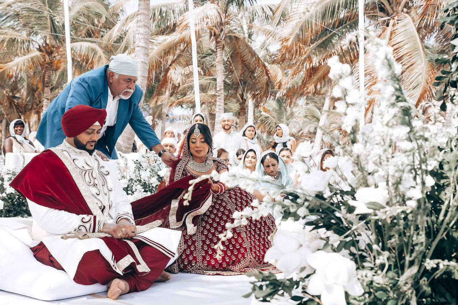 Beachfront wedding ceremony with tropical decor and white seating arrangements.