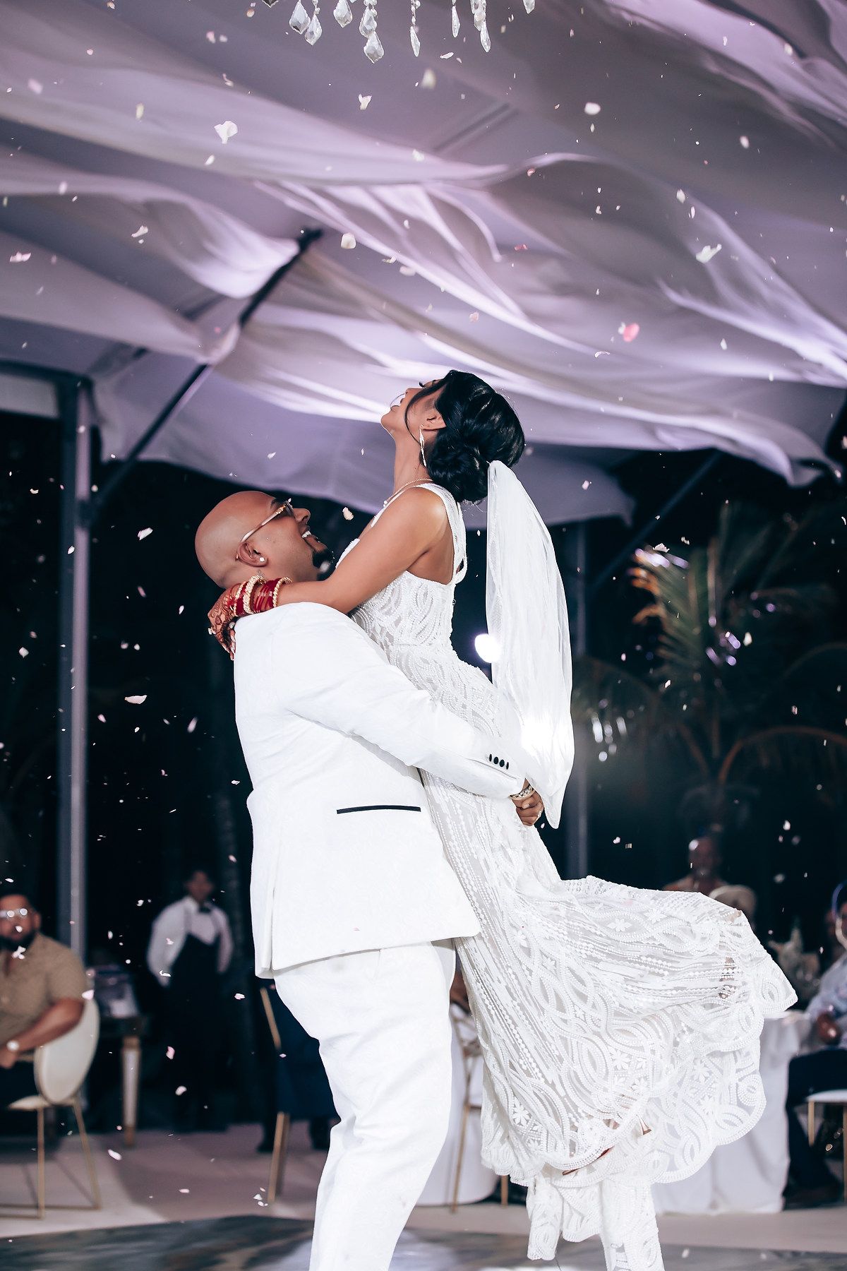 Newlyweds performing romantic dance moves under sparkling chandeliers at their wedding celebration.