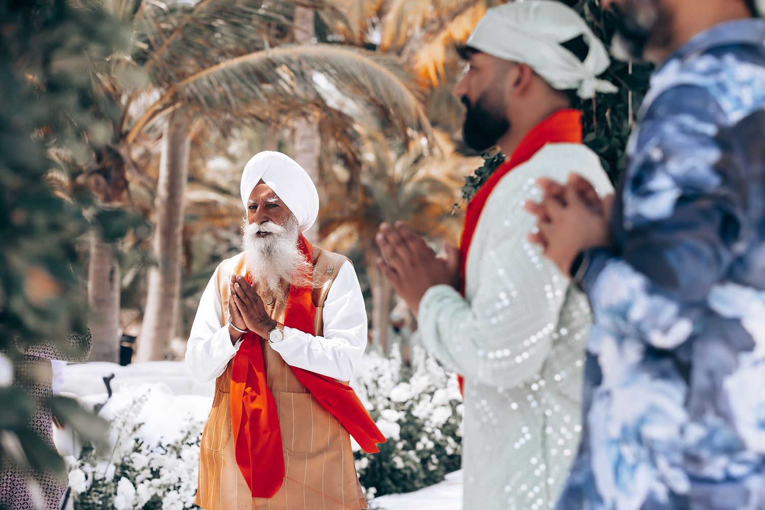 Wedding celebration scene with guests in traditional attire under a decorated outdoor canopy.