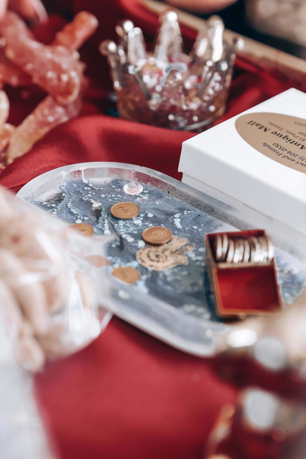 Wedding details featuring coins and decorative elements arranged on red fabric.