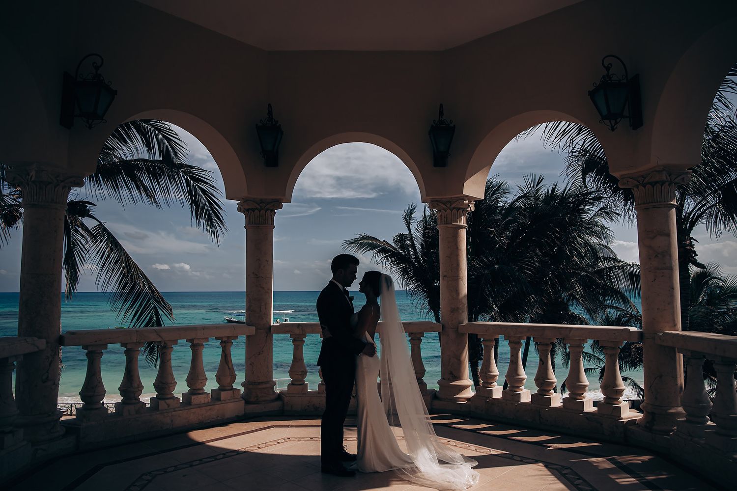 Elegant beachfront wedding venue with white stone arches framing the turquoise ocean view.