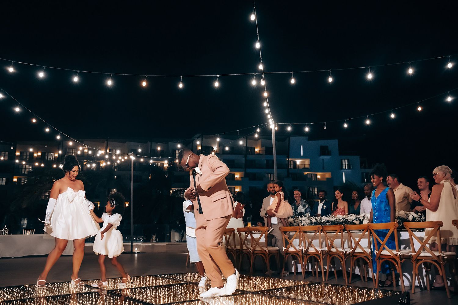 String lights illuminate an outdoor evening wedding reception setting.