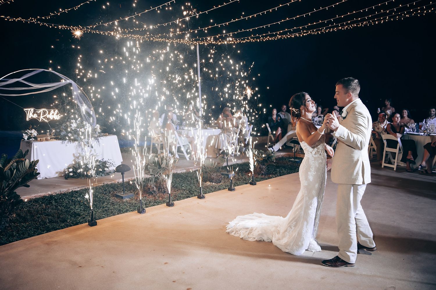 Wedding couple dances under sparkling lights during their reception celebration.