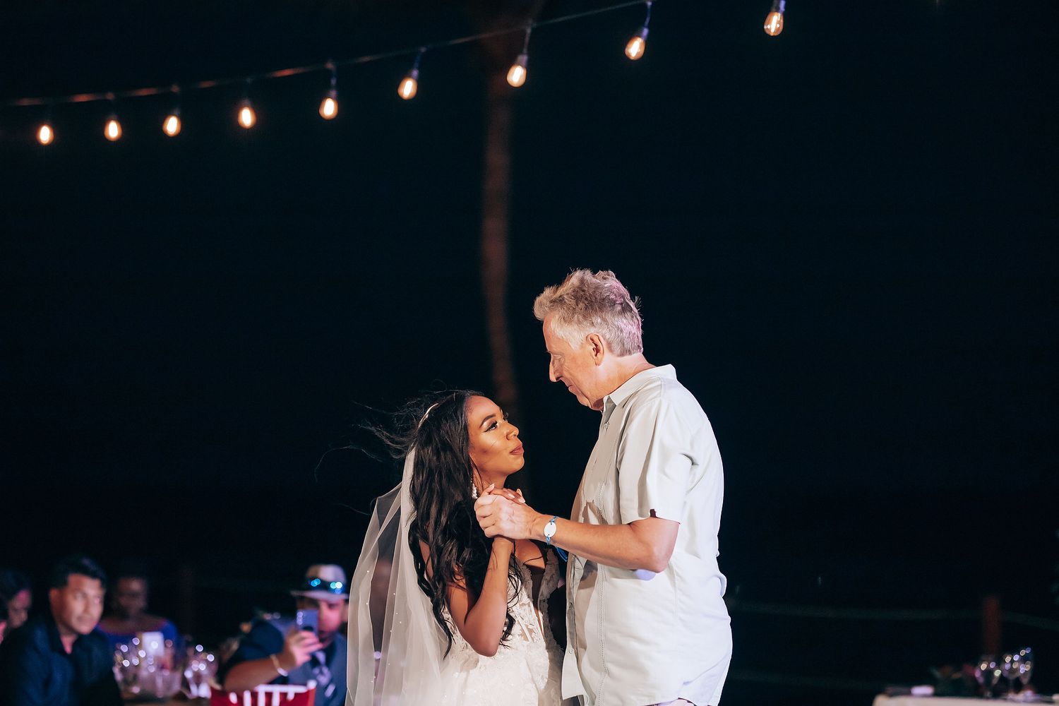 Wedding reception dance under string lights at night.