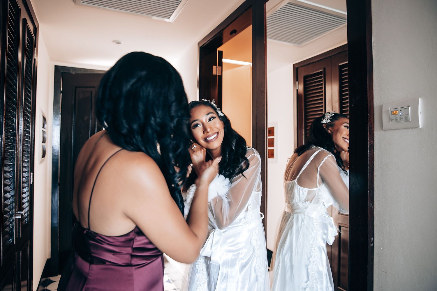 Wedding party getting ready in a bright indoor space with white walls and natural lighting.