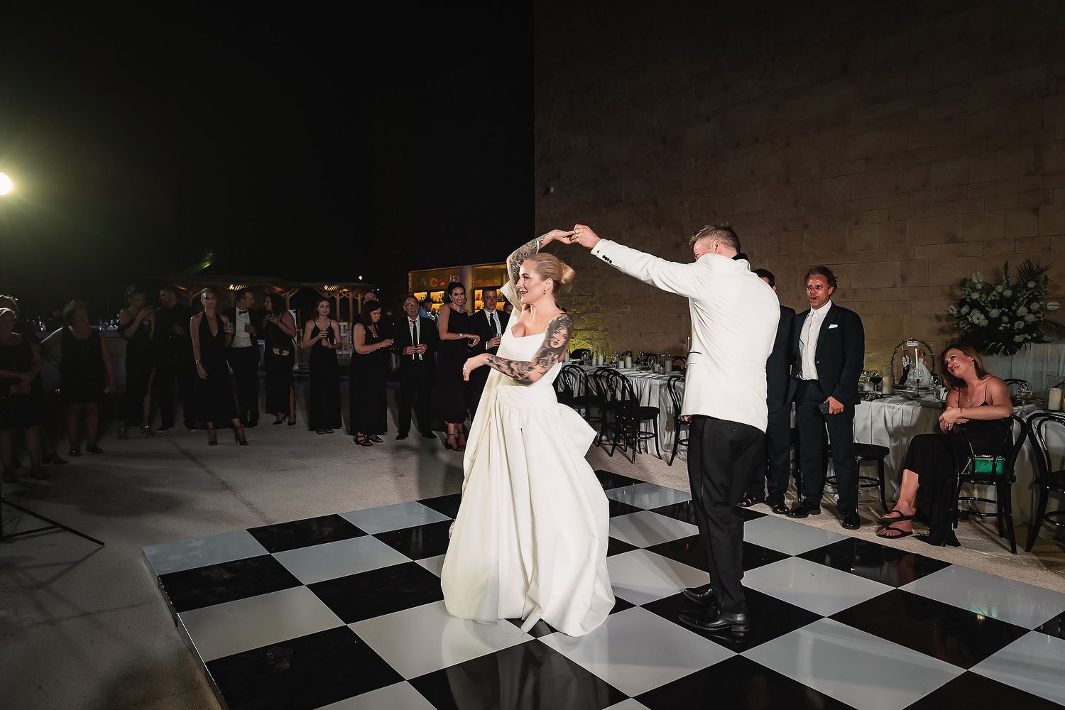 Evening wedding reception features dancing on dramatic black and white checkered floor.