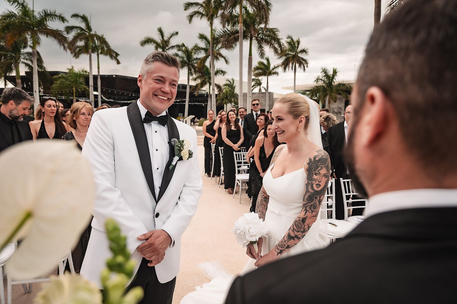Outdoor wedding ceremony moments captured with palm trees and waterfront views in the background.