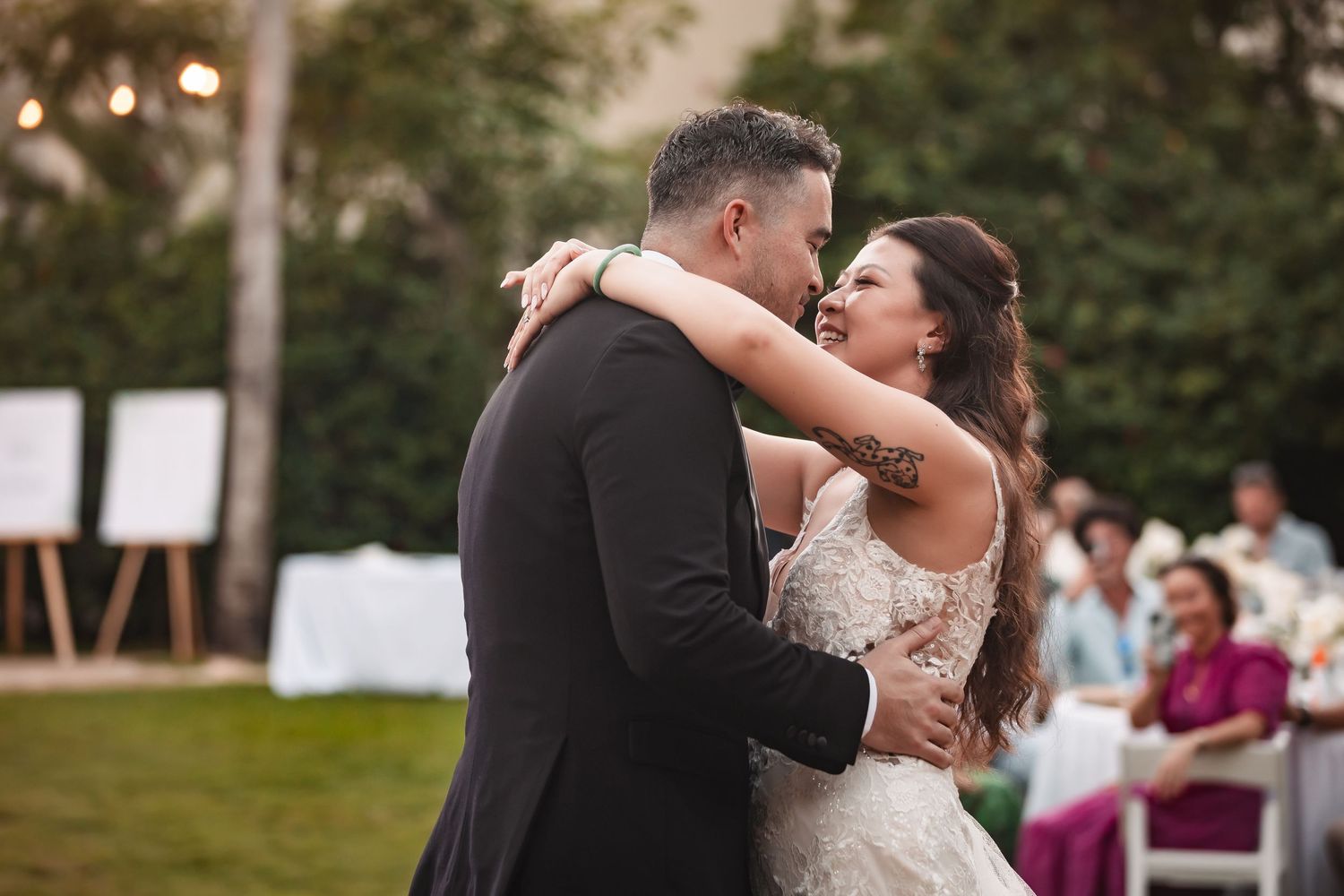 Newlyweds share an intimate dance moment surrounded by lush outdoor landscaping.