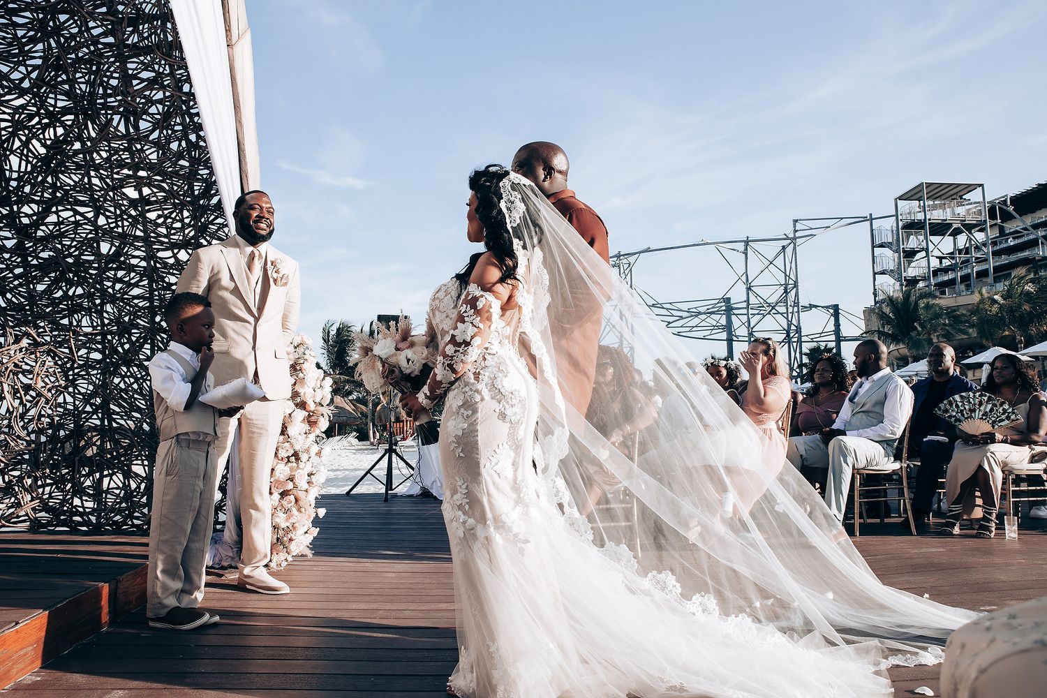 Wedding celebration on an oceanfront deck with flowing white dress and joyful dancing.