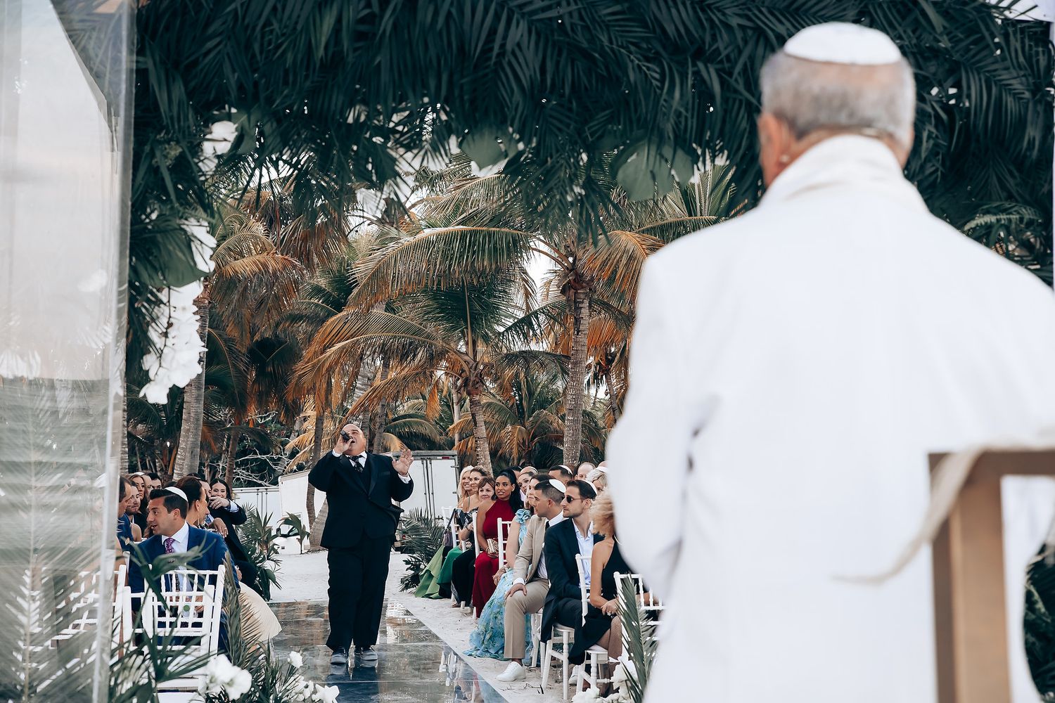Outdoor wedding ceremony setup with white chairs and floral arrangements.