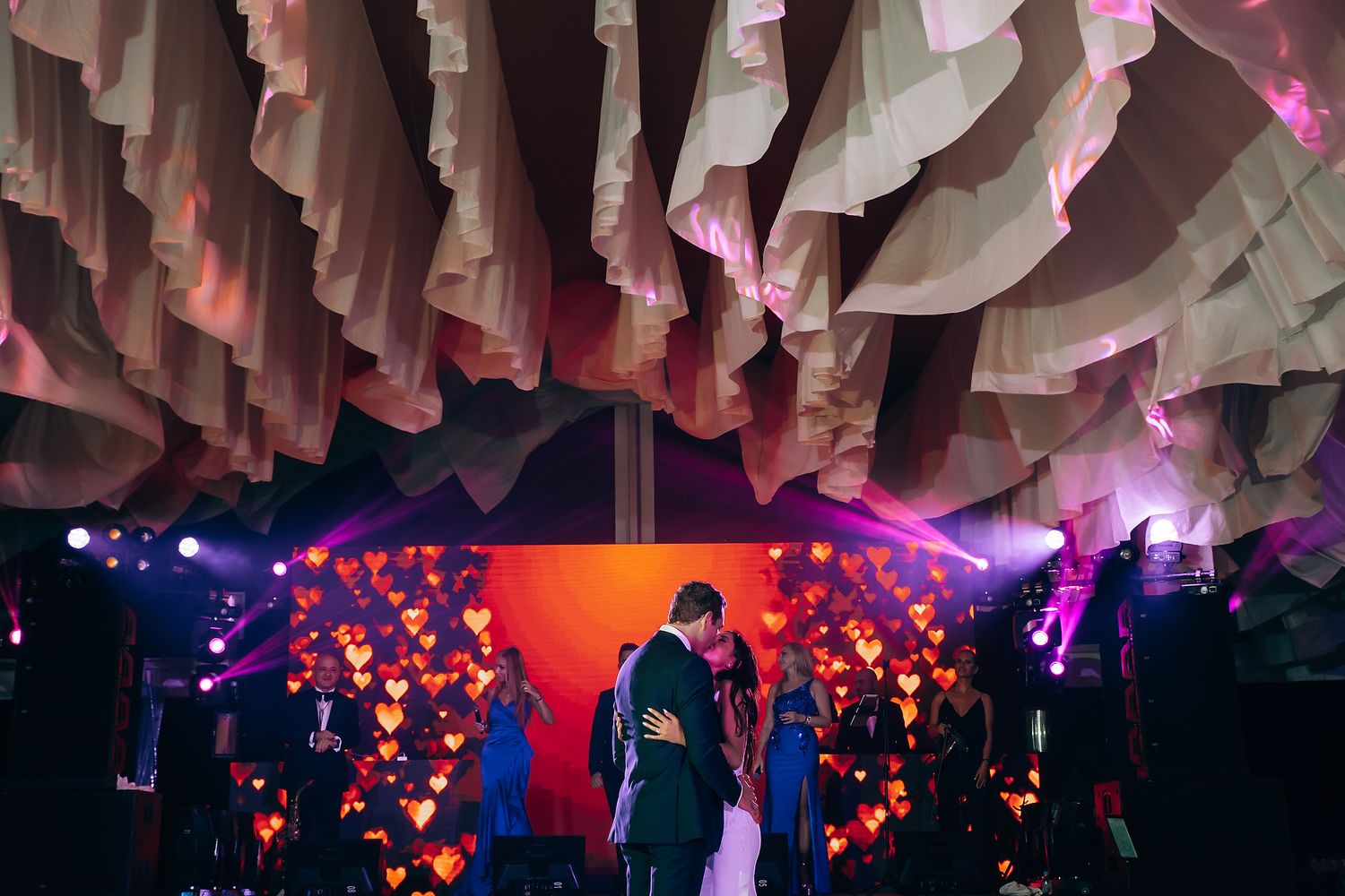 Wedding dance floor with romantic lighting and white fabric ceiling installation.