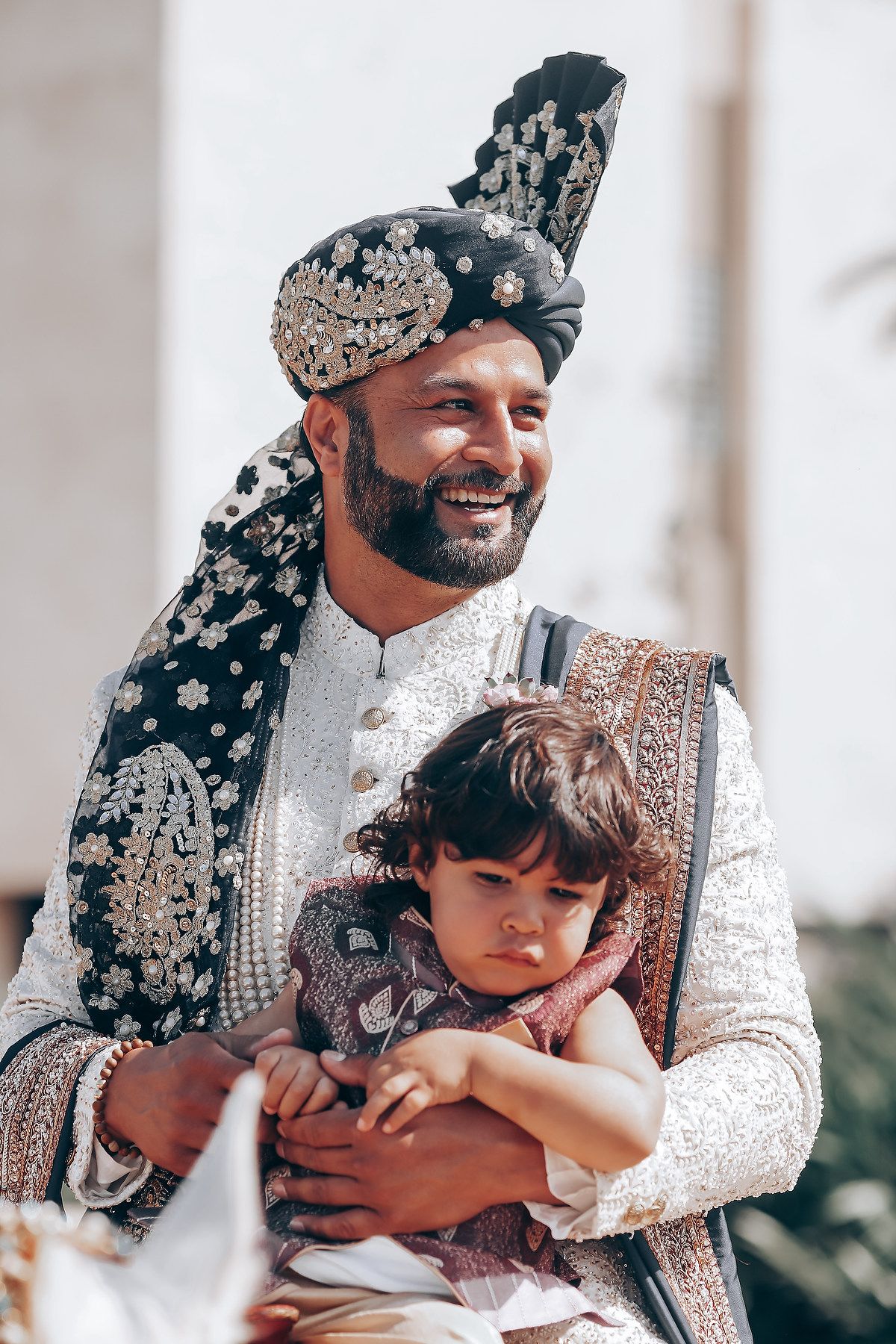 Traditional South Asian wedding attire with ornate turban and embroidered sherwani shown in warm sunlight.