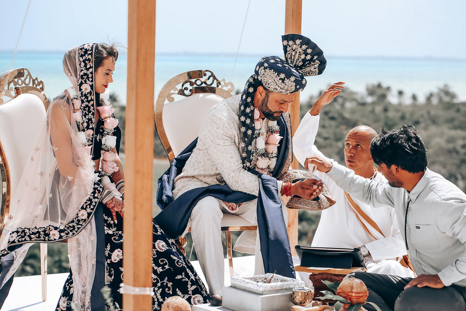 Wedding party celebrates outdoors under wooden beams at a scenic desert venue during golden hour.