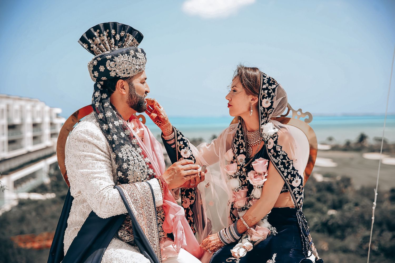 A couple shares a romantic moment on a beach during a wedding photoshoot with multiple scenic poses.
