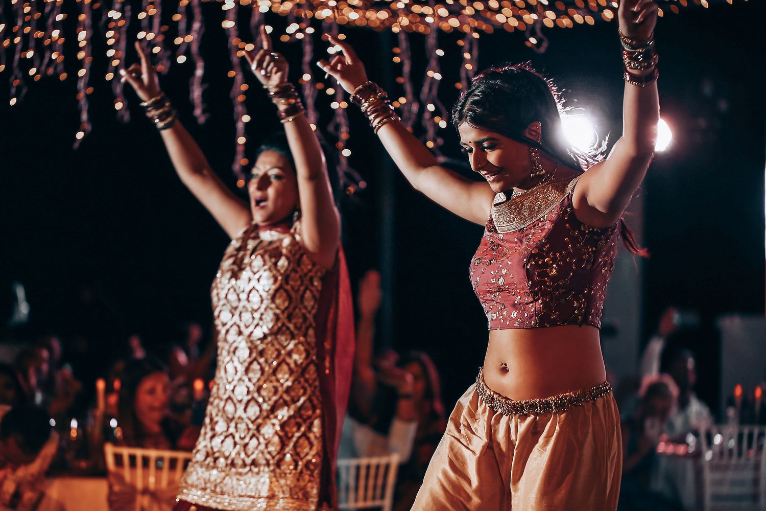 People dancing and celebrating at a nighttime event with colorful lighting and festive atmosphere.
