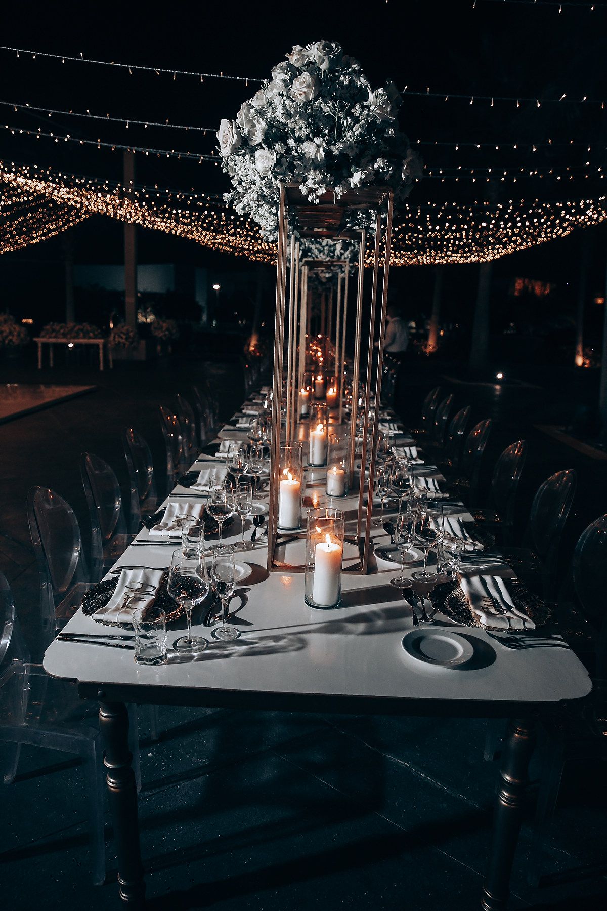 Elegant wedding reception tables with crystal chandeliers and string lights creating a romantic atmosphere.