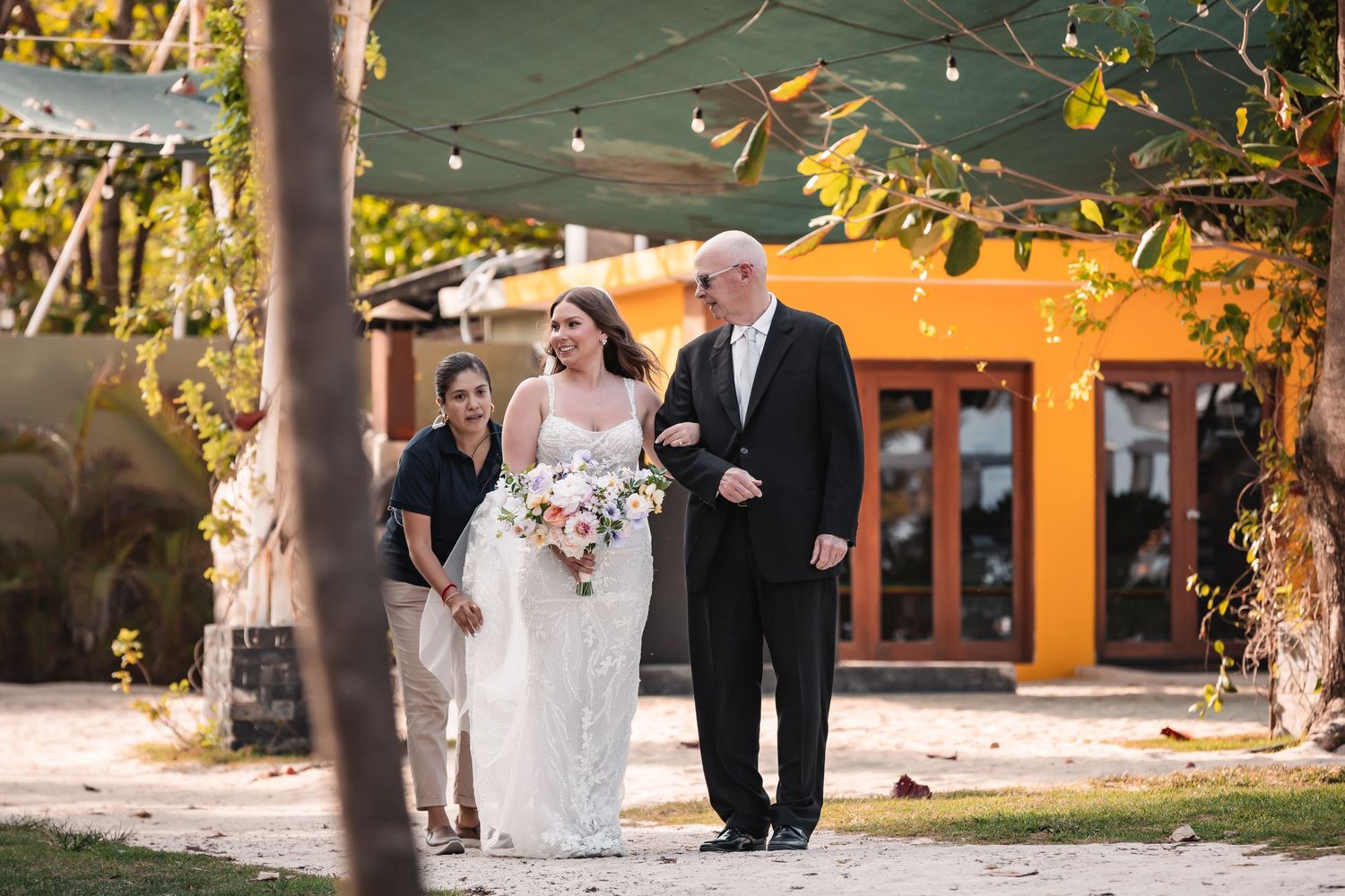 Sunset wedding ceremony with string lights and tropical landscaping.