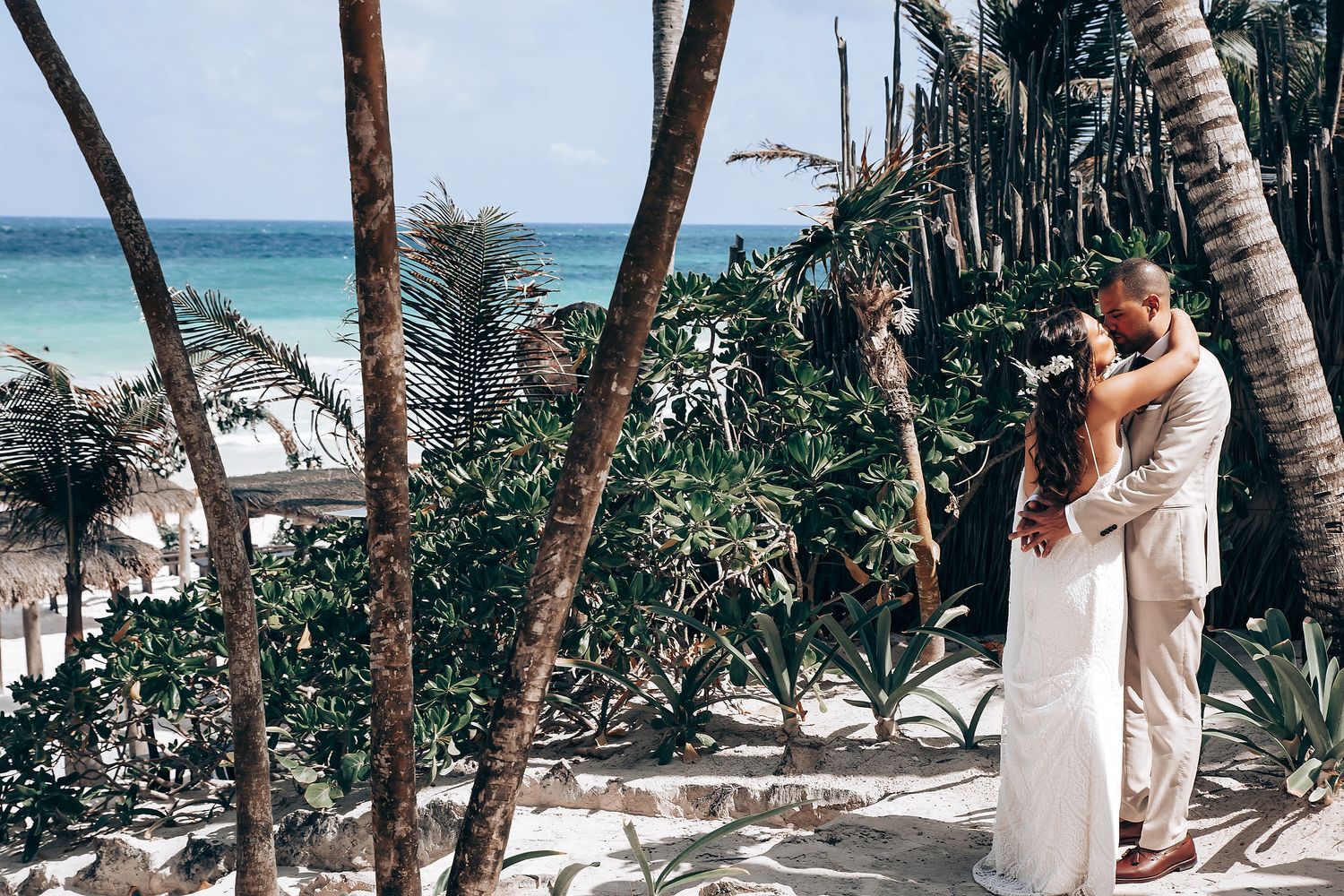 A series of palm trees line a pristine white sand beach with turquoise waters in the background.