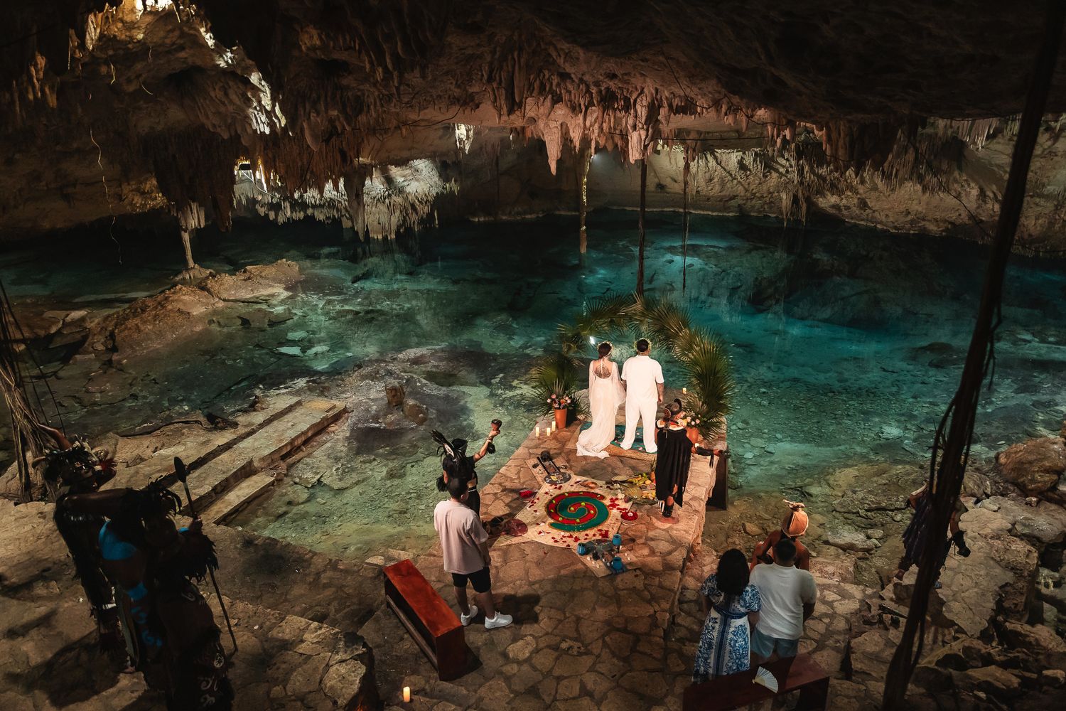 Scenic cave wedding venue with turquoise cenote waters and romantic lighting setup.