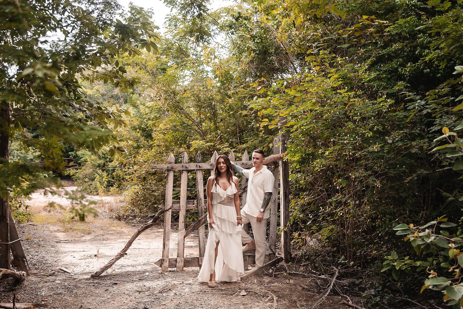 A romantic woodland photo session featuring a couple in light colored outfits walking among autumn trees.