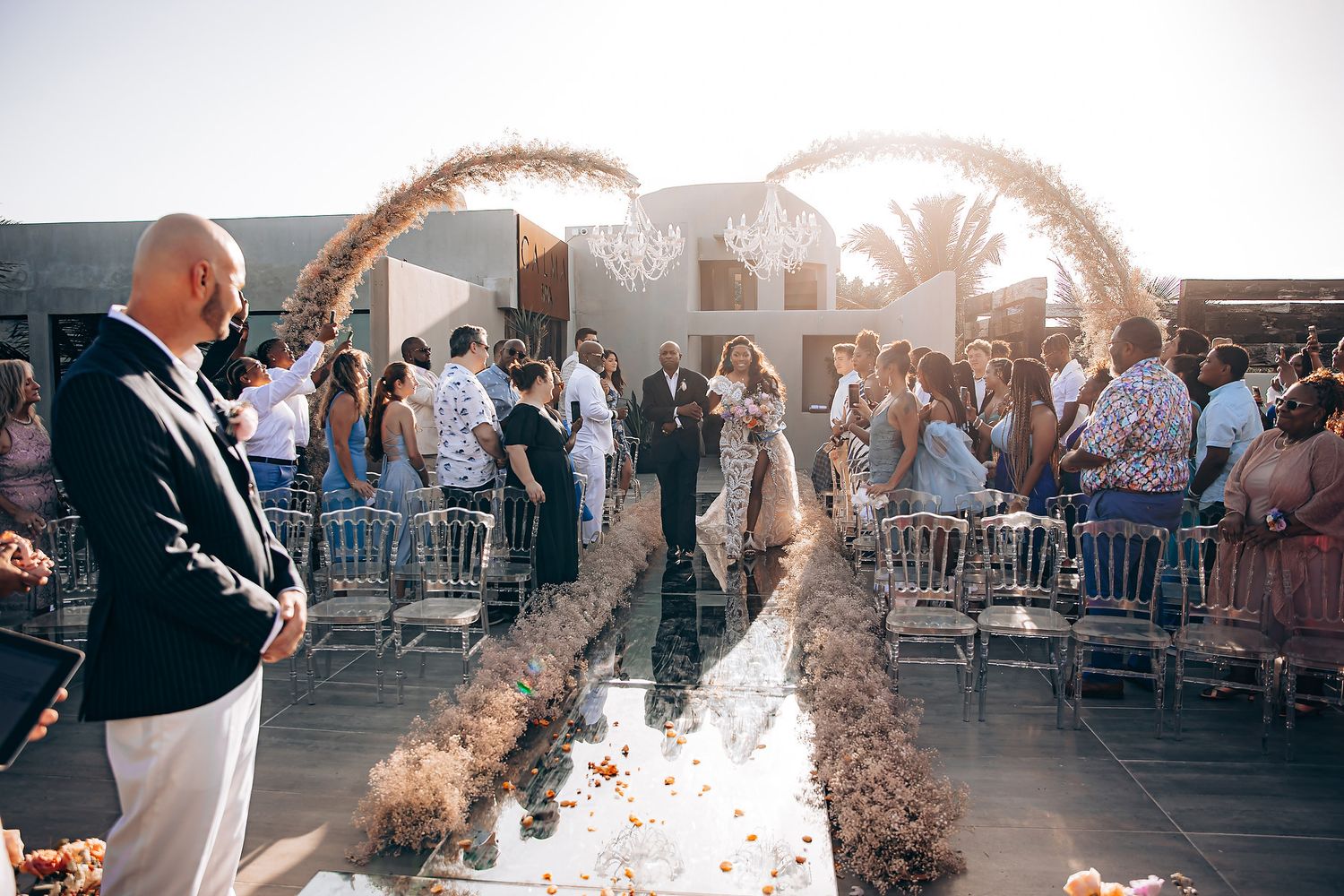 A couple celebrates their first dance at a wedding reception as guests toss confetti in the sunlit venue.