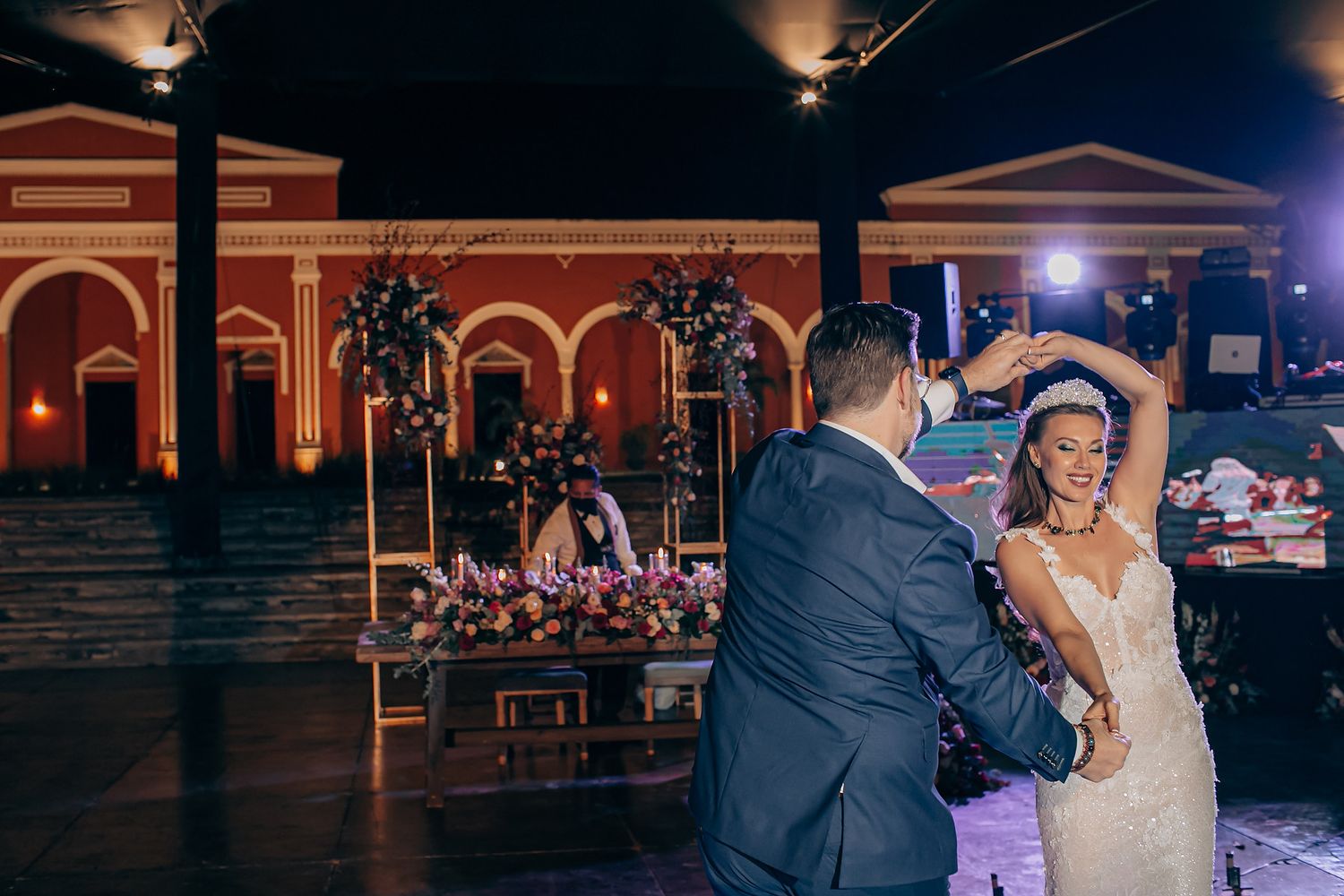 A couple shares their first dance at an elegant wedding reception venue with illuminated arches.