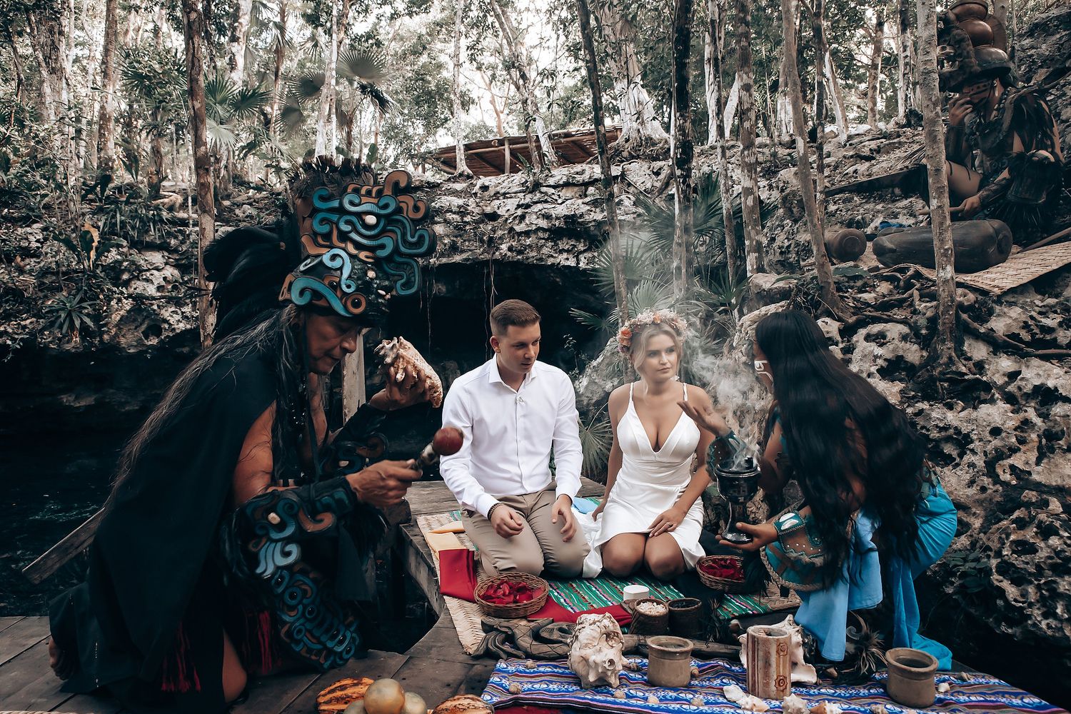 Outdoor gathering with blankets and decorations set up in a wooded area.