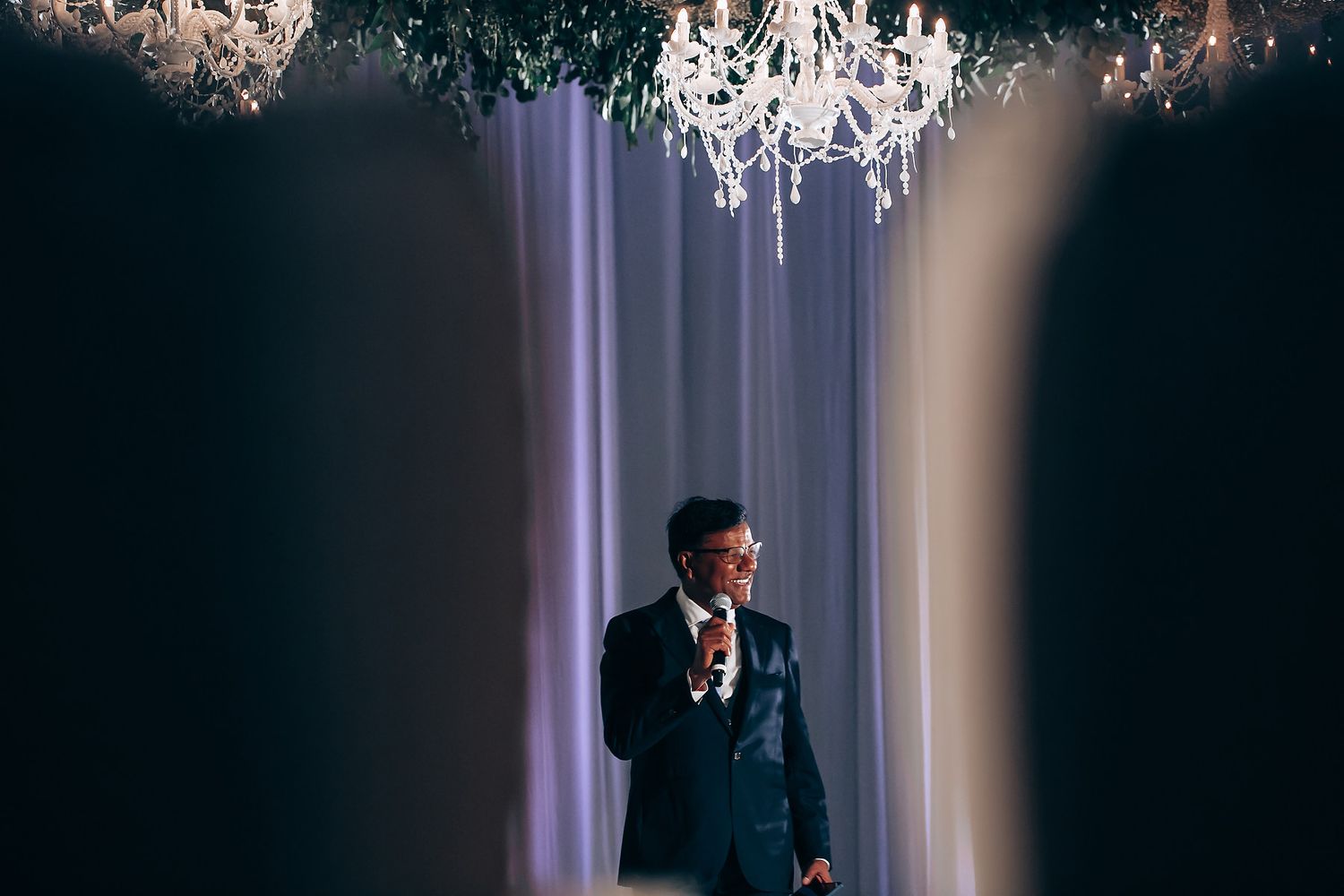 Dramatic portrait under a crystal chandelier at an elegant wedding reception.