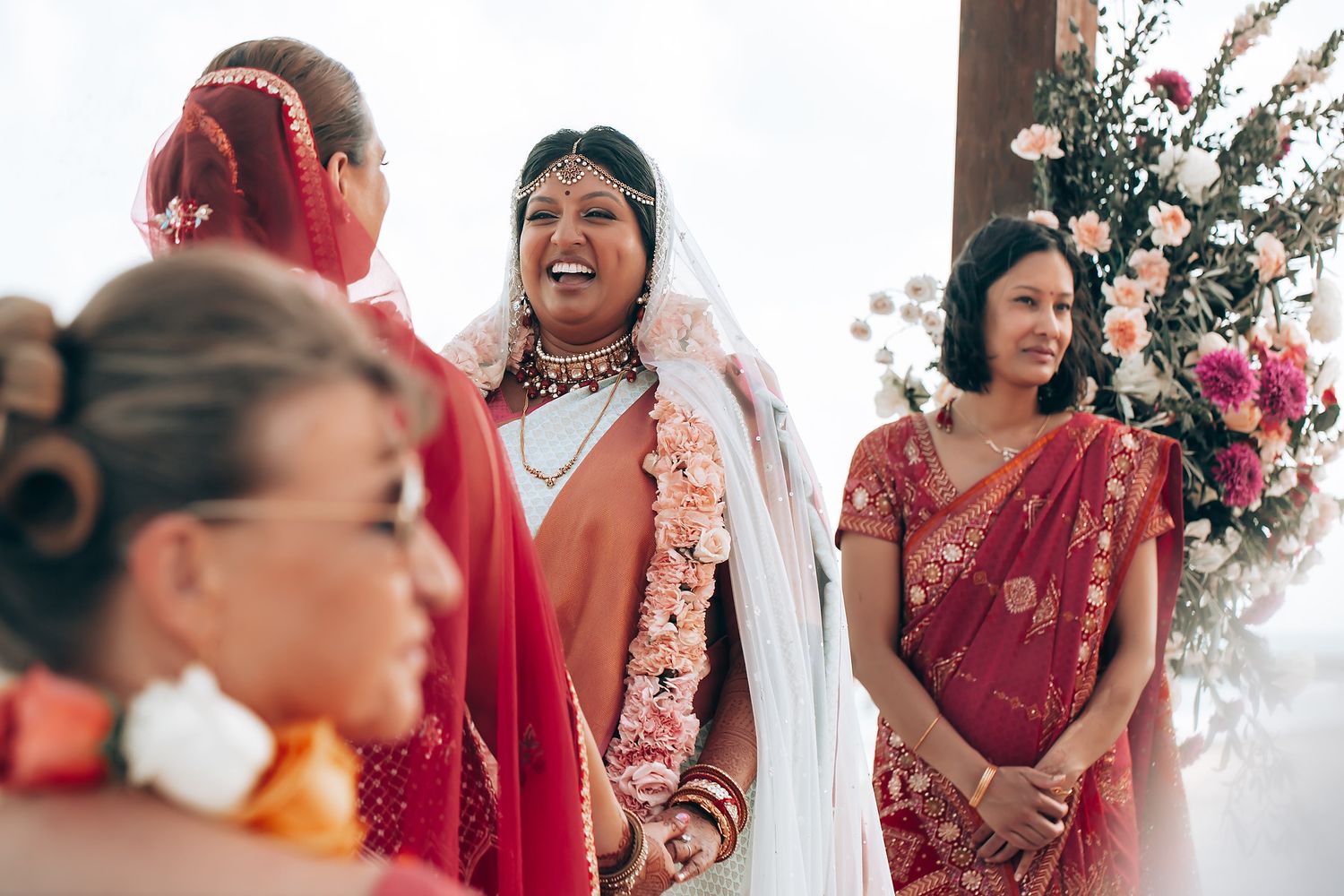 A joyous moment captured during an outdoor Indian wedding ceremony with floral decorations.