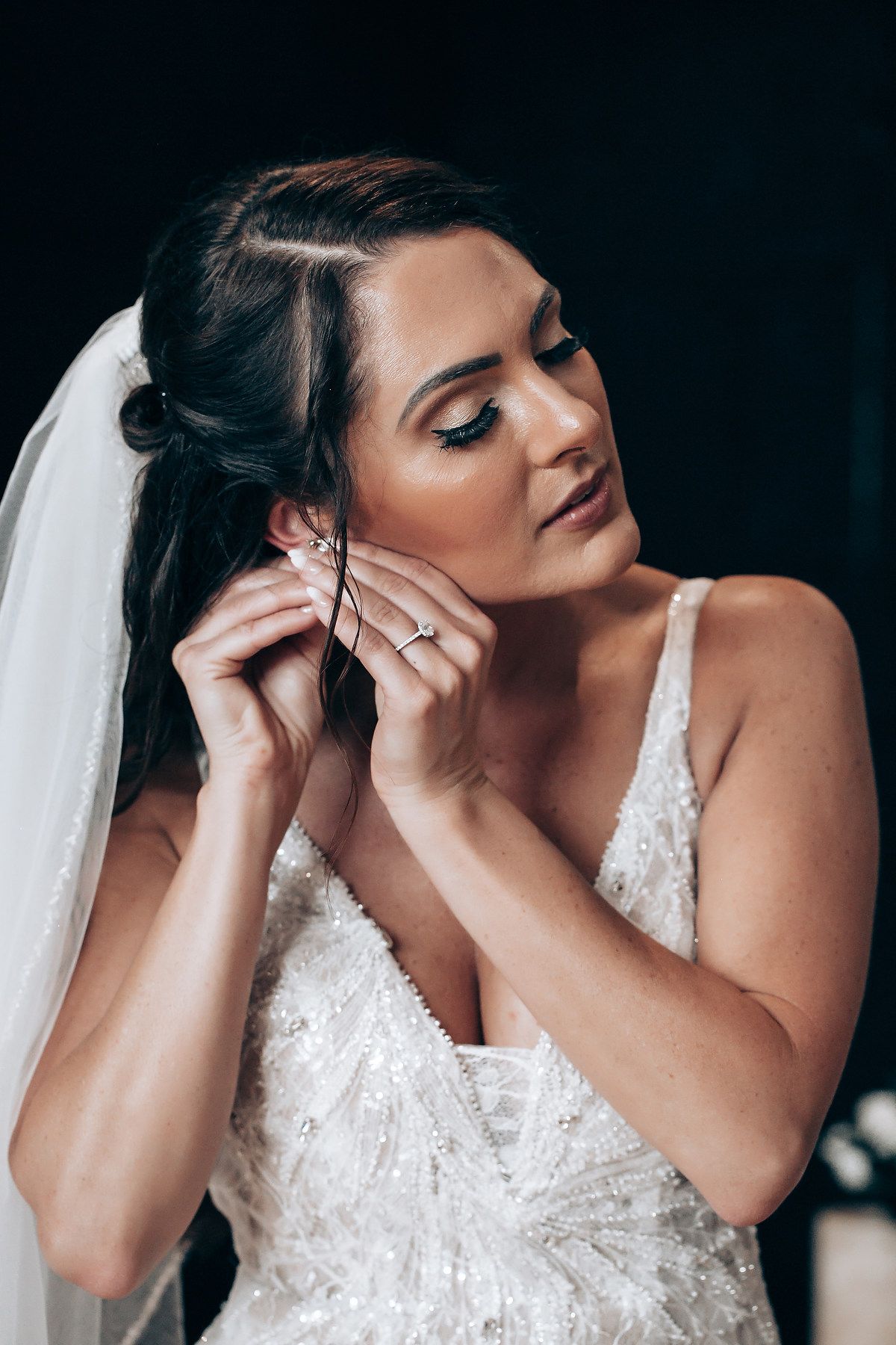 Close-up artistic bridal portrait showing delicate lace details and a flowing veil.