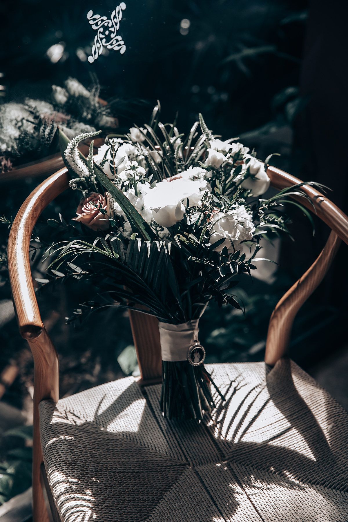 Elegant floral arrangements cast dramatic shadows on a textured surface in moody lighting.