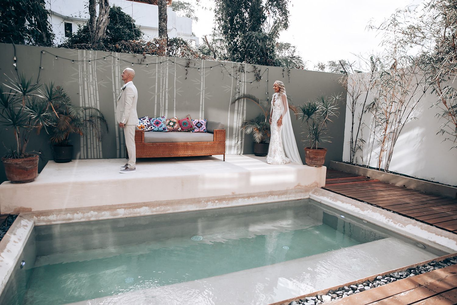 A tranquil poolside setting with white decor and tropical plants surrounding a small swimming pool.