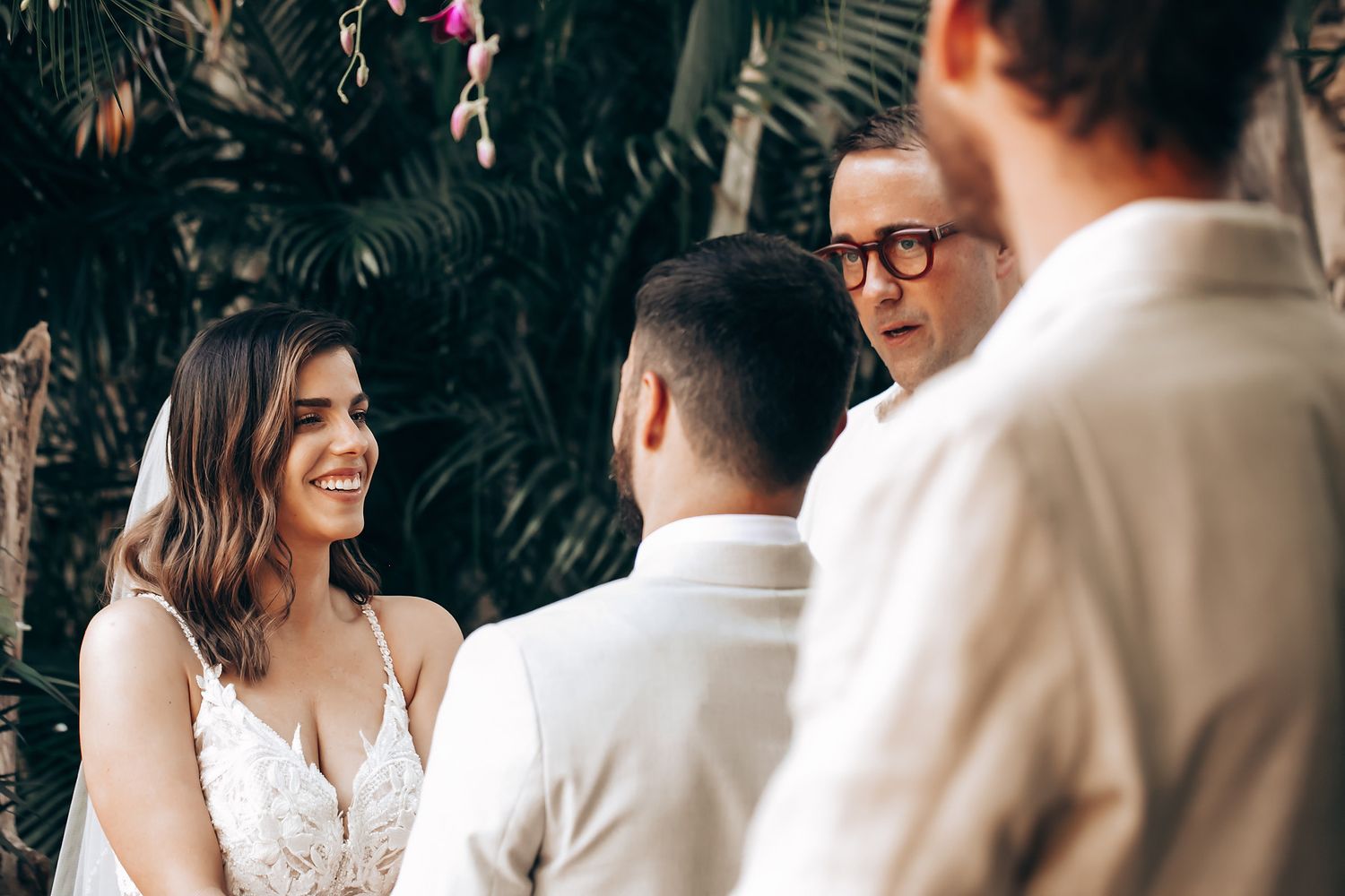 Intimate wedding ceremony moment under a wooden pergola decorated with flowers and greenery.