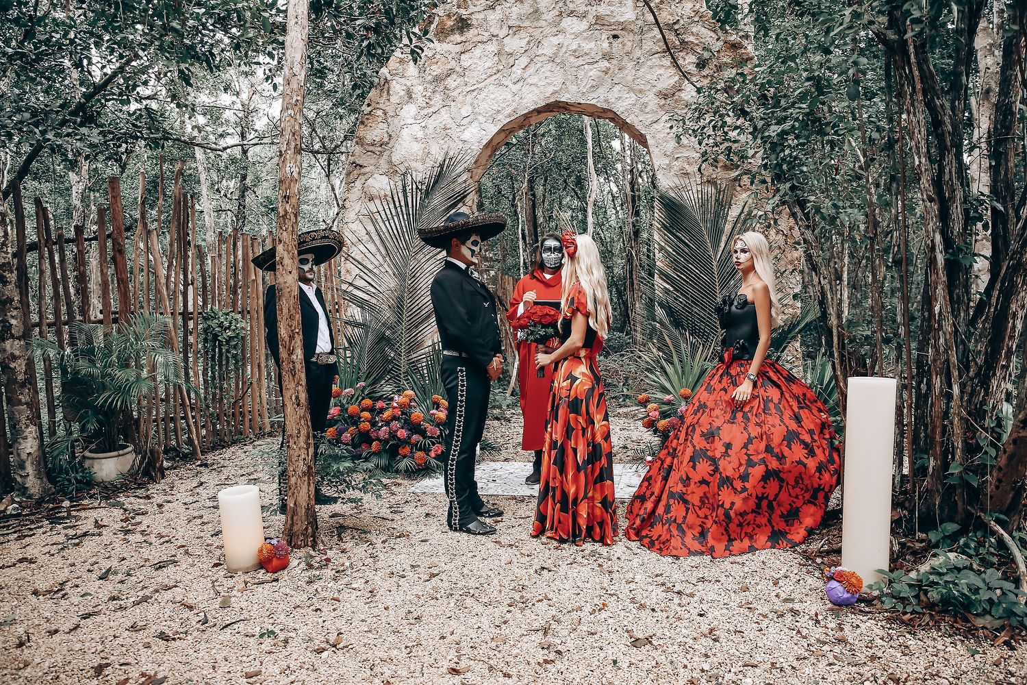 A gothic wedding ceremony setup under a stone arch with red and black themed decorations.