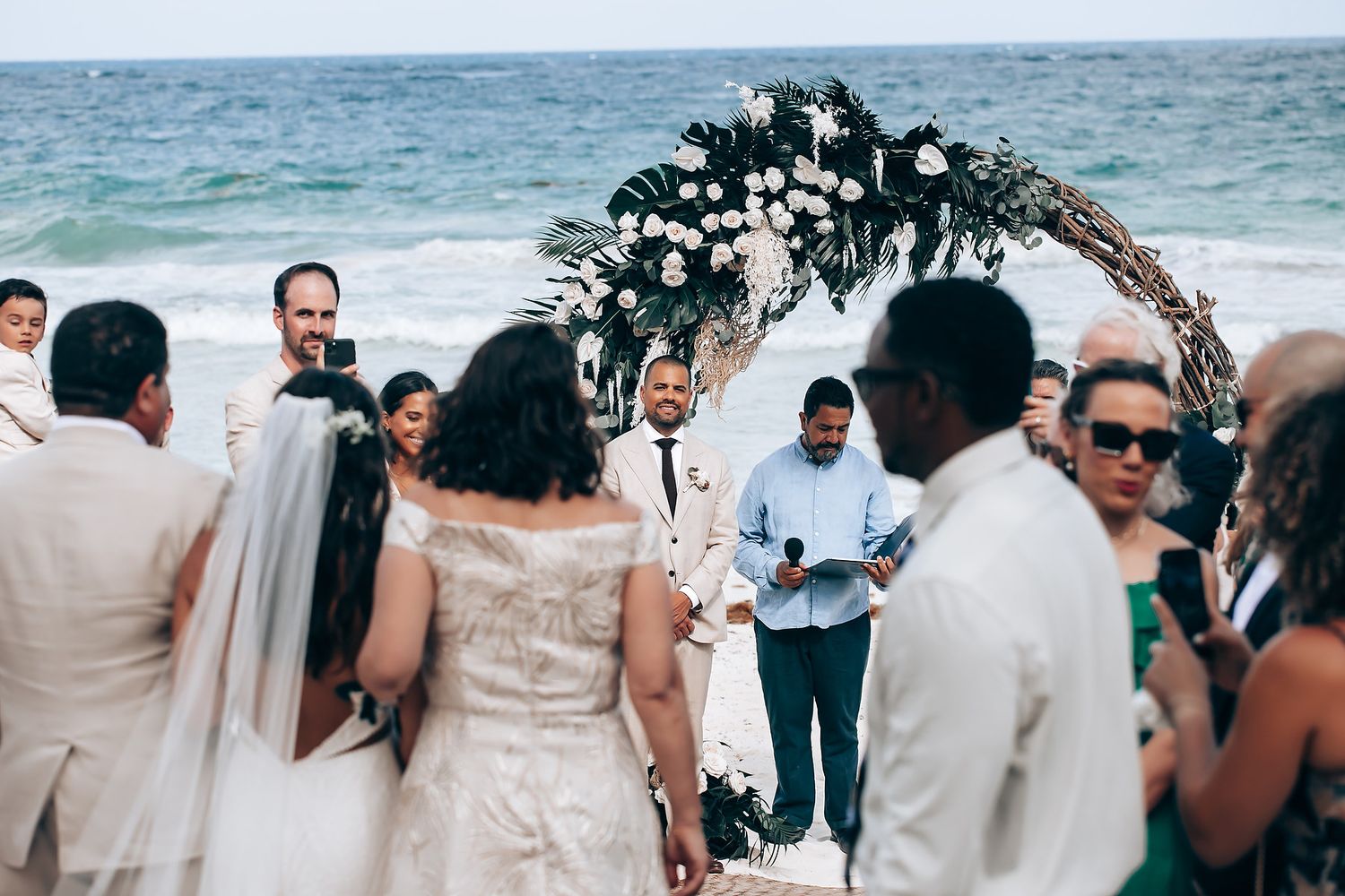 Wedding celebration on a tropical beach with palm trees and ocean views.