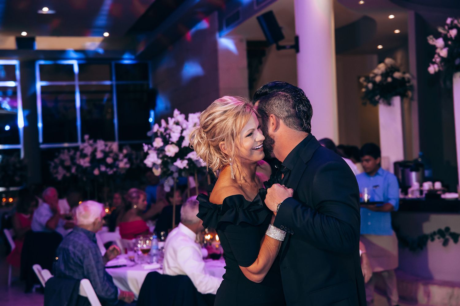 Couples dancing at wedding reception with blue and purple lighting creating romantic atmosphere.