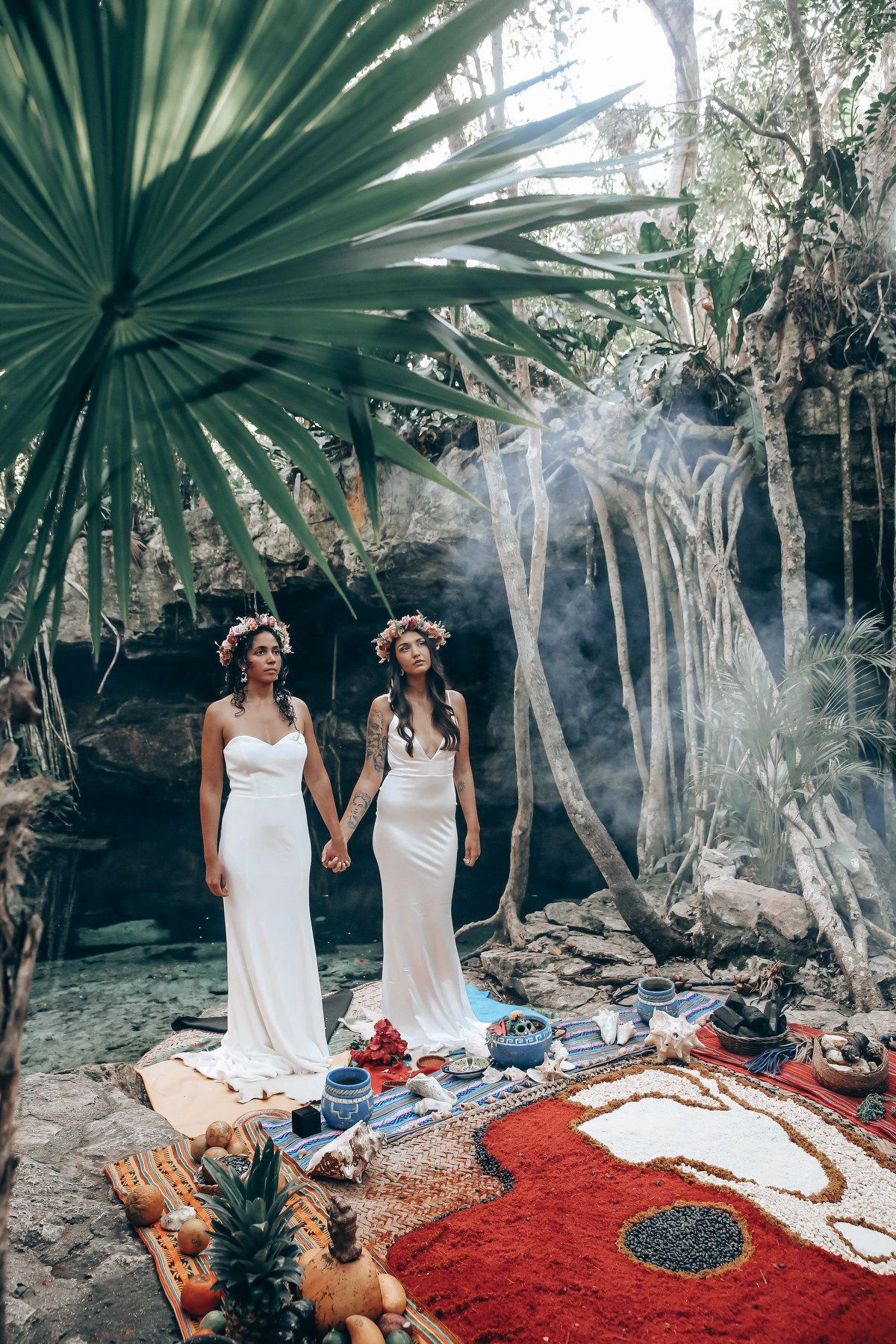 A romantic ceremony setup with a red carpet and tropical decor in a jungle cenote setting.