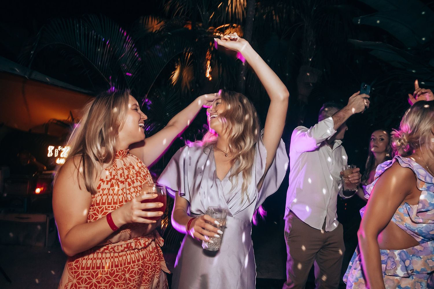 Wedding reception guests dancing and socializing under atmospheric purple lighting.