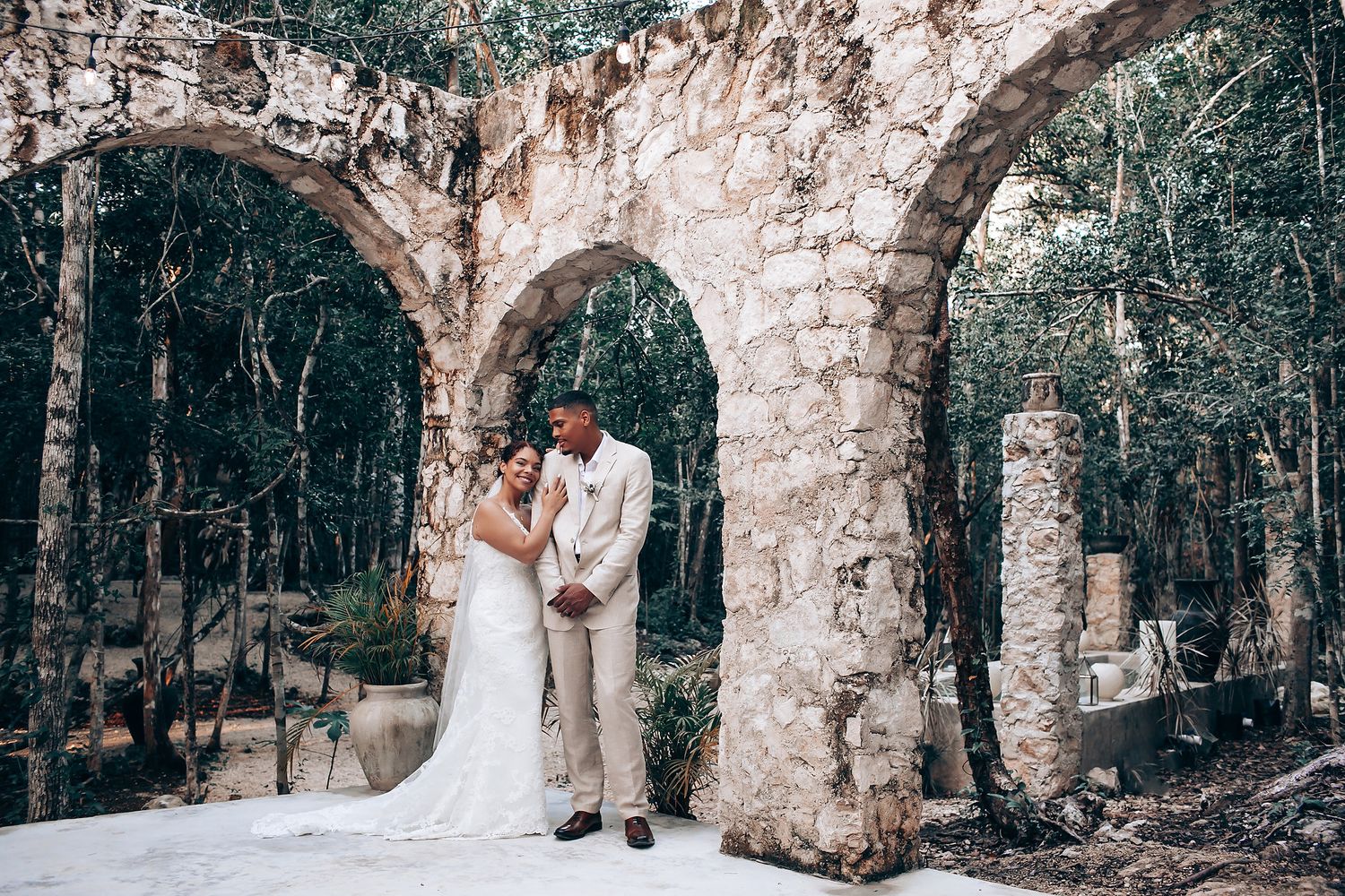 A wedding photo collection featuring a stone archway adorned with flowers in a natural forest setting.